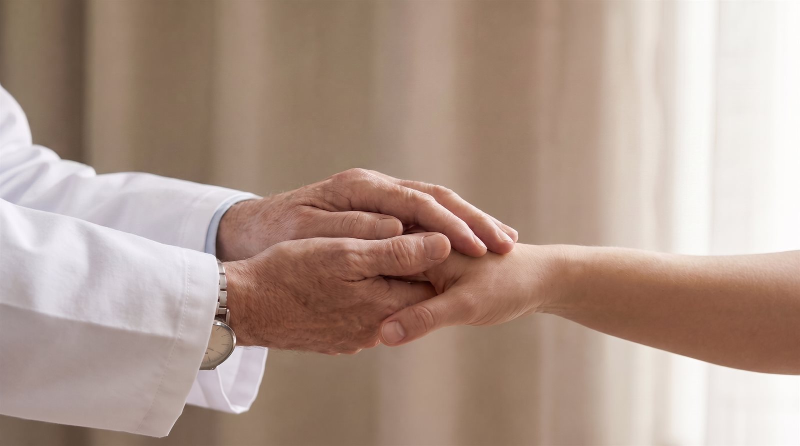 Un médico sostiene con ambas manos la mano de un paciente