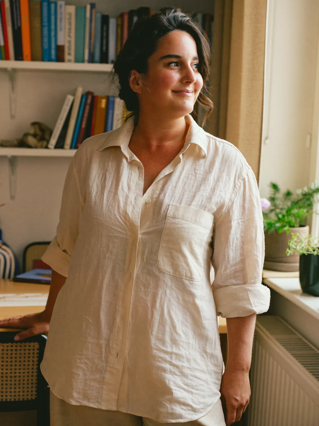 Mujer sonriente en su despacho, junto a la ventana